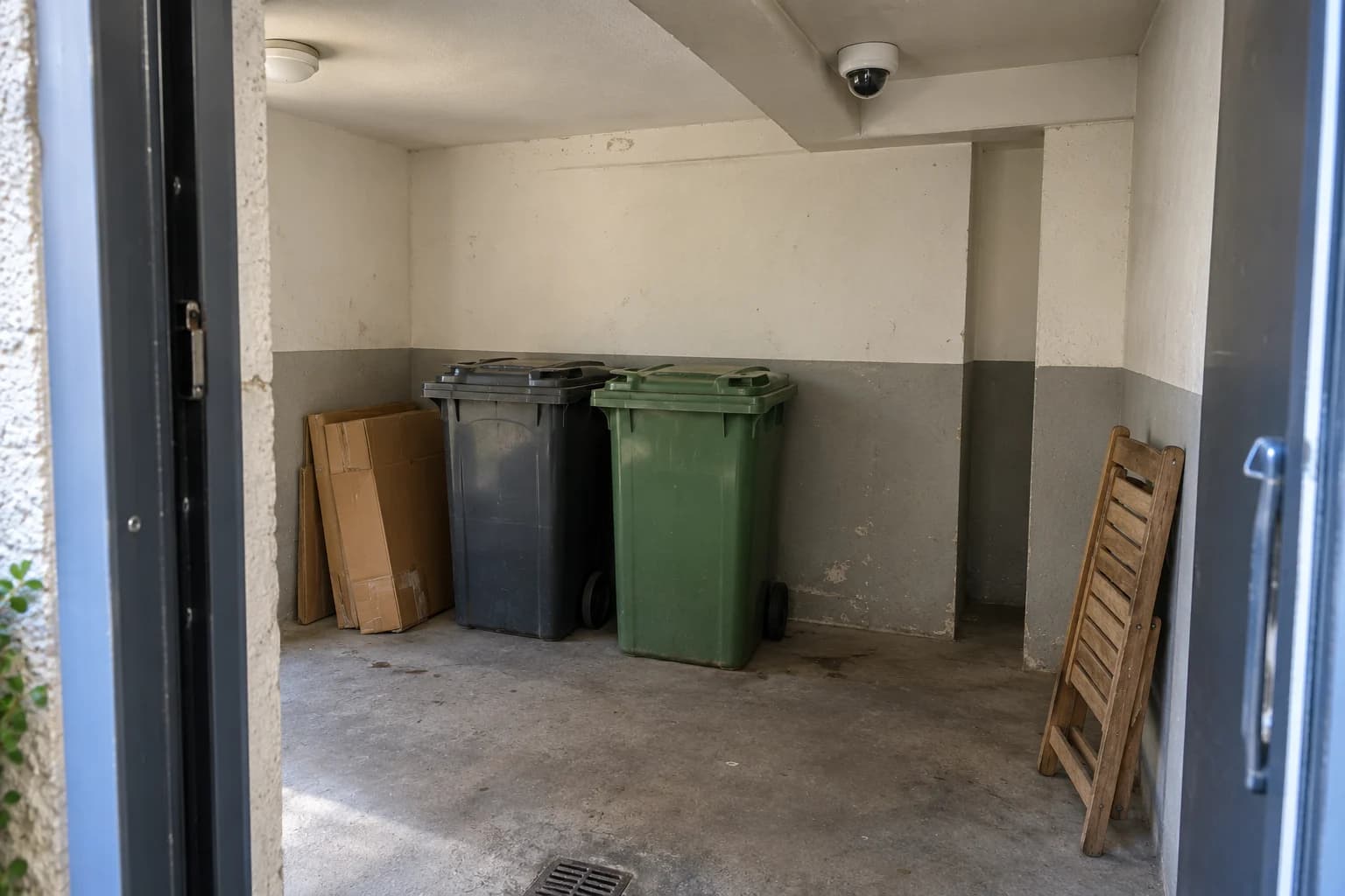 Local de collecte avec bacs fermés, encombrants à évacuer et caméra sur un support fixe
