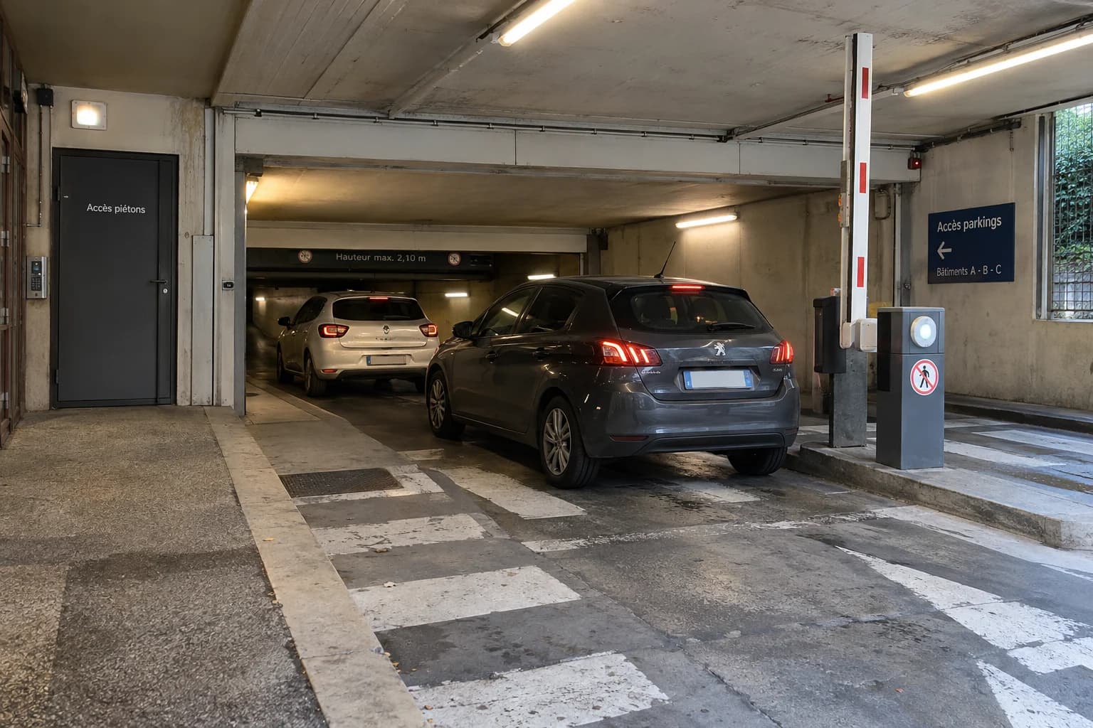 Scène fictive générée : deux voitures à l’entrée d’un parking avec barrière relevée et accès piéton séparé