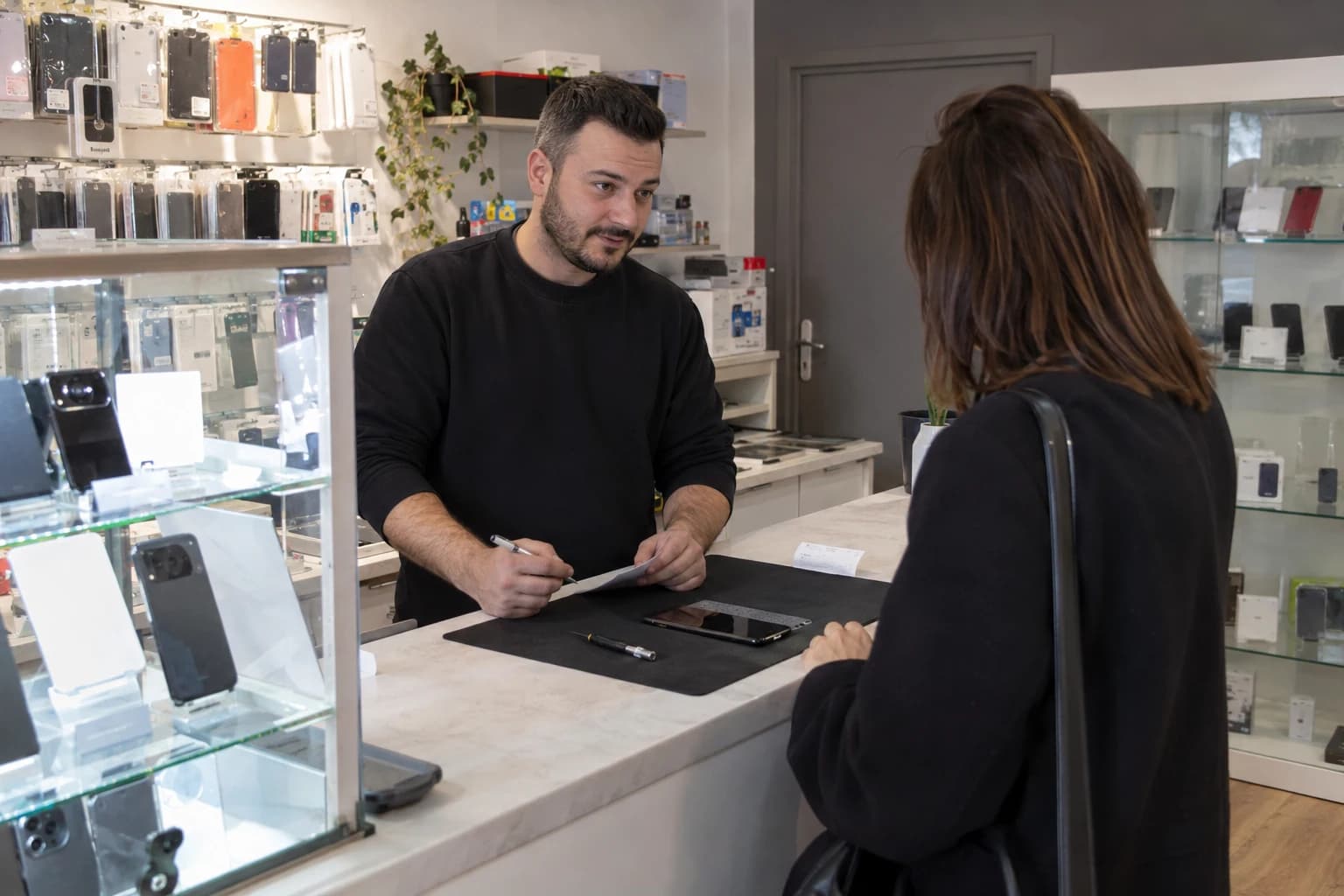 Illustration d’une boutique de téléphonie fictive : dépôt d’un appareil au comptoir